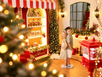 Irmãos sorrindo costas com costas na frente da vitrine com quebra-nozes da Vila de Natal em Tijucas